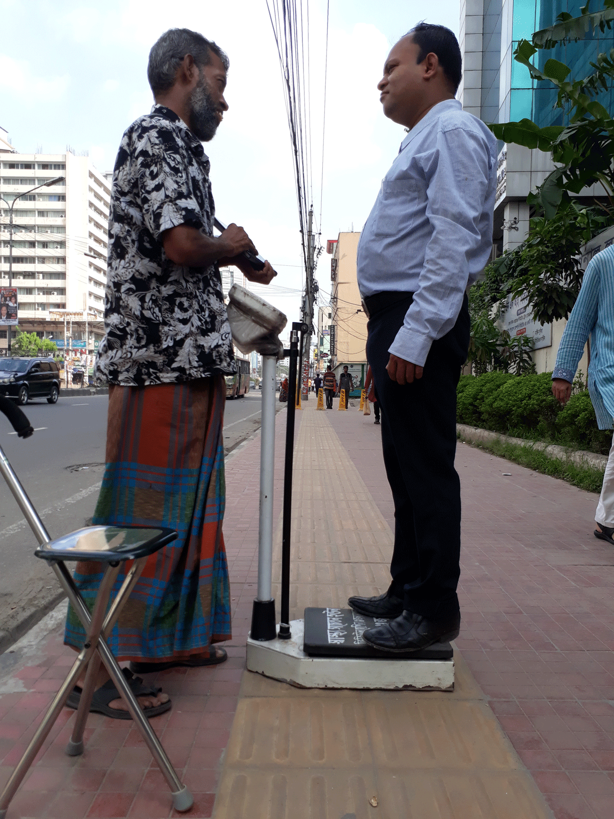 Fashion designer Mahbubur Rahman (R) takes his weight Rashedul (L) looks on in Karwan Bazar, Dhaka on 17 August. Photo: Shameem Reza
