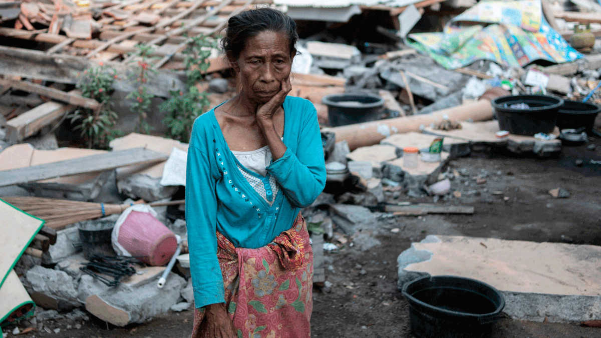 A woman stares by her collapsed house in the village of Labu Pandan on Indonesia`s Lombok island on 22 August, 2018 after a series of recent earthquakes. Photo: AFP