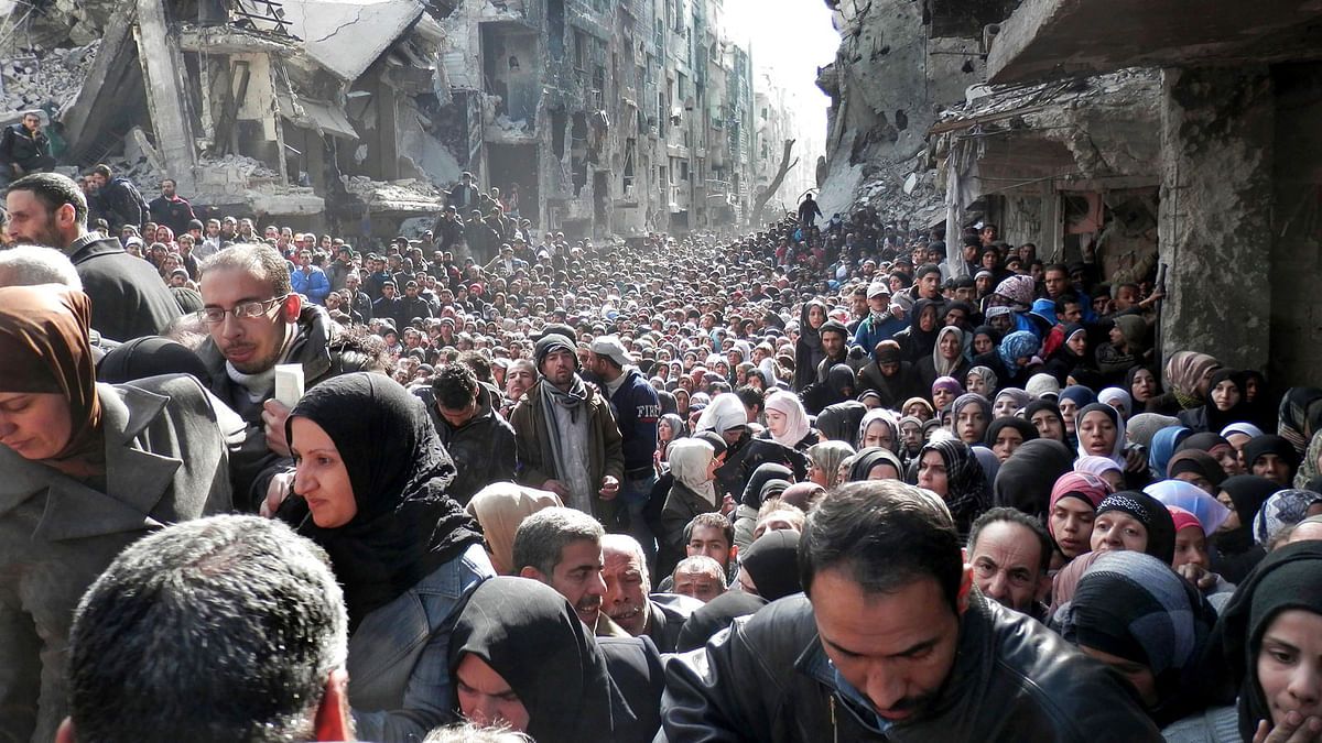 In this 31 January 2014 file photo released by the United Nations Relief and Works Agency for Palestine Refugees (UNRWA), shows residents of the besieged Palestinian camp of Yarmouk, lining up to receive food supplies, in Damascus, Syria. Photo: AP