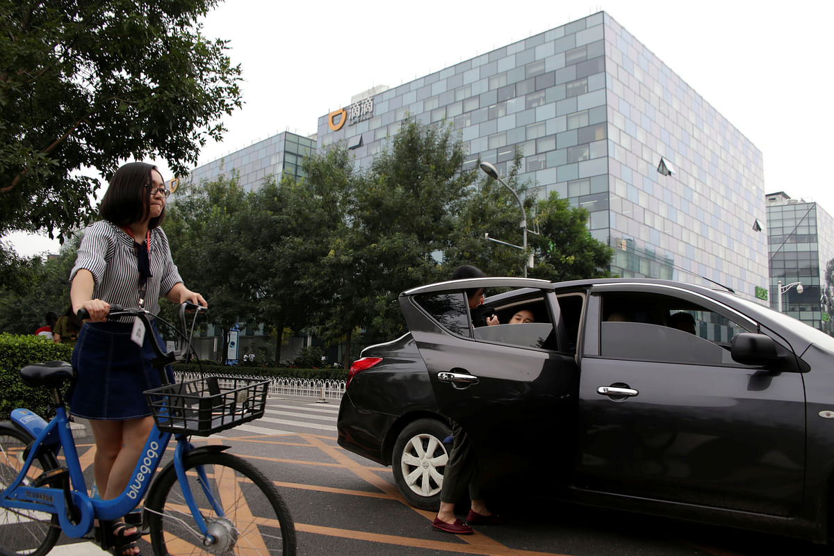 Passengers sit into a car provided by Didi Chuxing`s Kuaiche service in front of its headquarters building in Beijing, China on 28 August 2018. Photo: Reuters