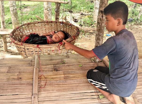 A boy rocks his little brother to sleep in a cradle as his parents are busy in Jhum cultivation. Agarbagan, Kamilachhari, Rangamati on 28 August. Photo: Supriya Chakma