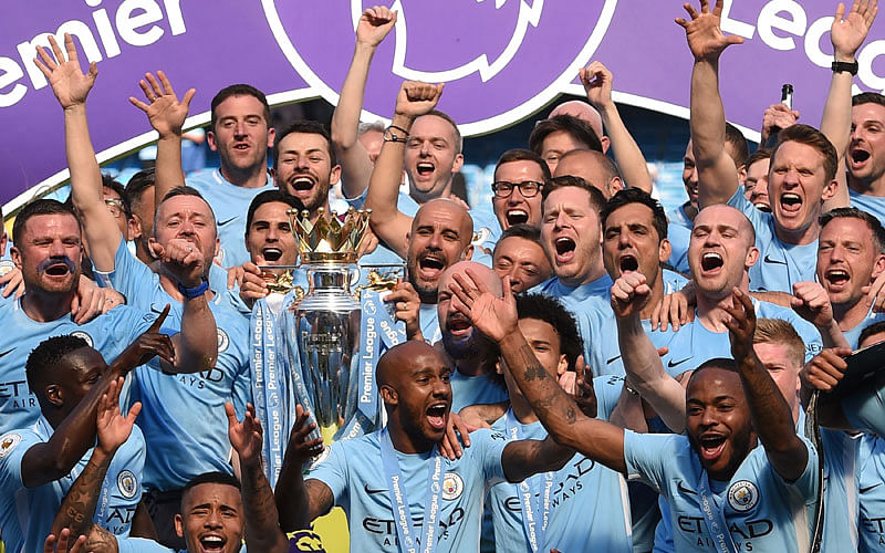 In this file photo taken on May 6, 2018 Manchester City's Spanish manager Pep Guardiola (C) holds the Premier League trophy on the pitch with Manchester City players after the English Premier League football match between Manchester City and Huddersfield Town at the Etihad Stadium in Manchester. Just 10 years after he bought struggling Manchester City, Sheikh Mansour has the satisfaction of knowing his billions have transformed the club from a national punchline to the kings of English football. AFP