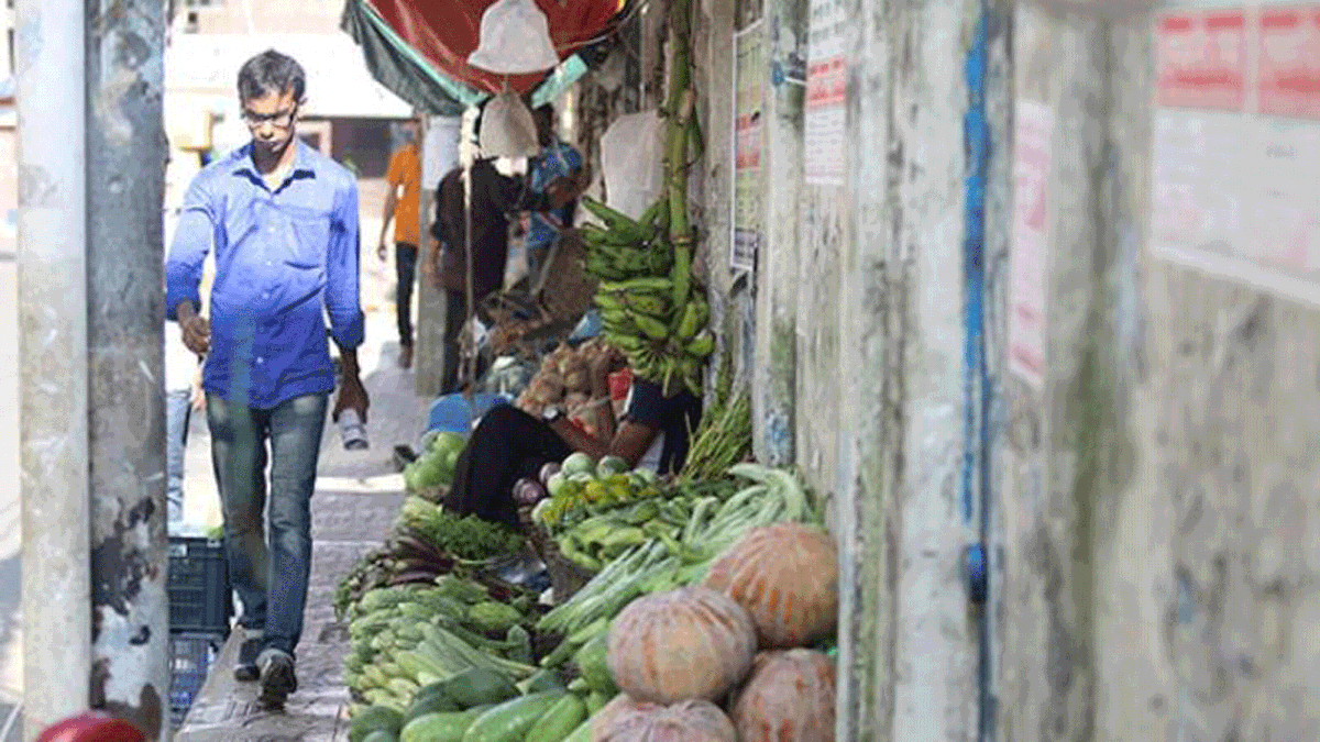 A pedestrian finds difficulty walking on the pavement of Hatirpool, Dhaka due to the vegetables shops sitting there on 31 August. Photo: Abdus Salam