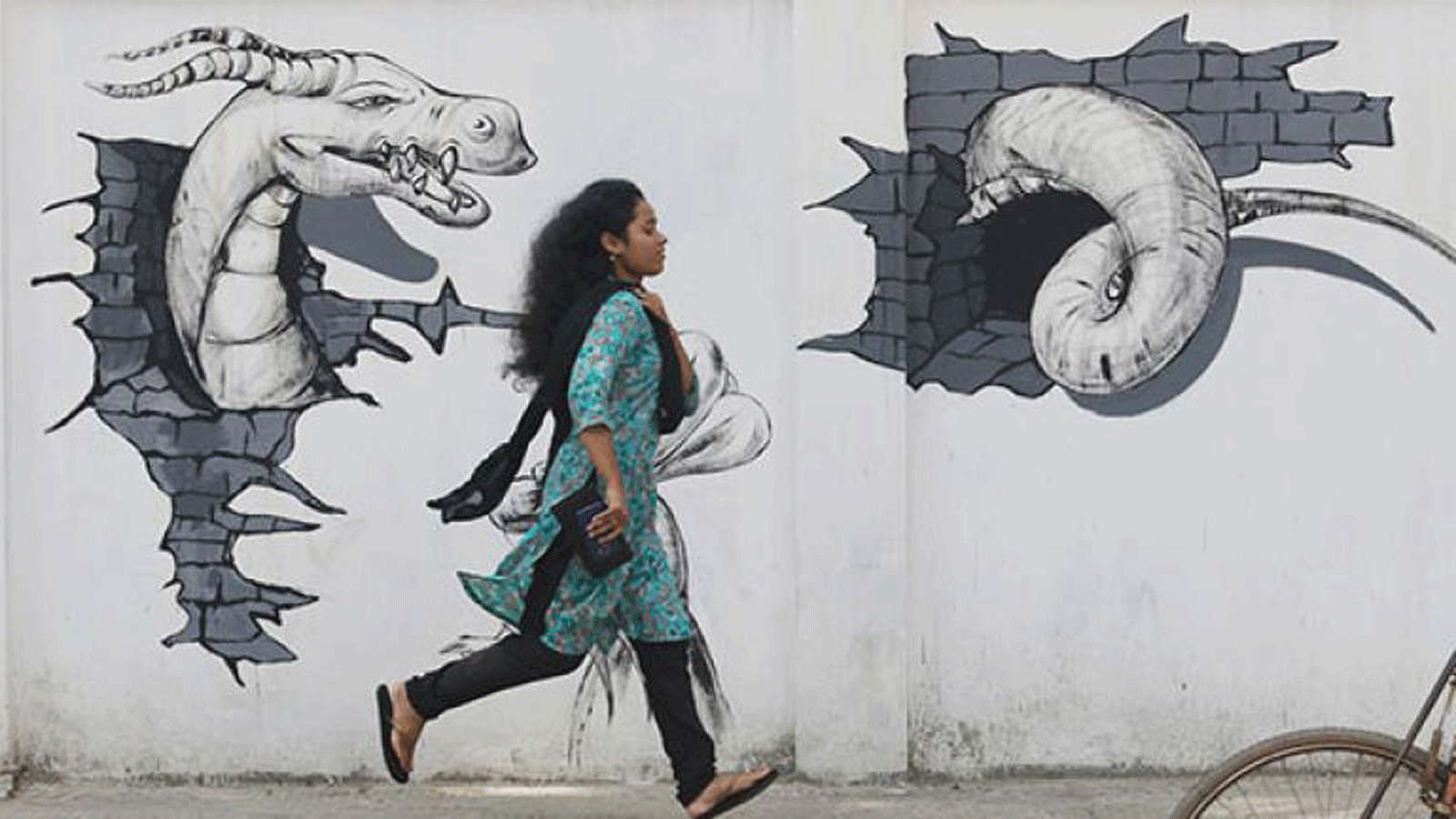 A woman runs past graffiti on the wall of Shamsun Nahar Hall of Dhaka University on 31 August. Photo: Abdus Salam