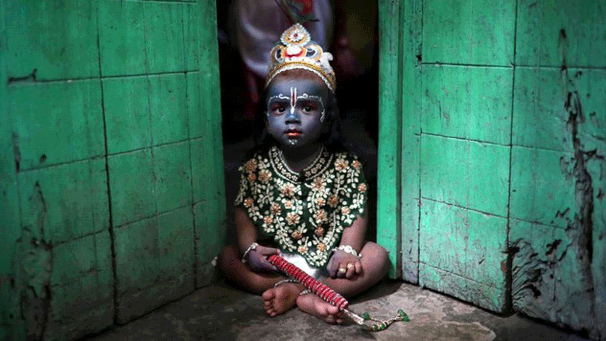 A child sits on a doorstep, dressed as Lord Krishna during Janmashtami festival, which marks the birth anniversary of Lord Krishna in Dhaka, Bangladesh, 2 September 2018. Photo: Reuters