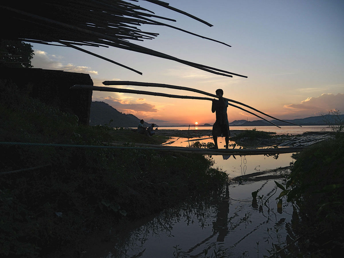 An Indian labourer carries bamboo at a bamboo market at the banks of the river Brahmaputra in Guwahati, the capital city of India`s northeastern state of Assam on 3 September 2018. -- Photo: AFP