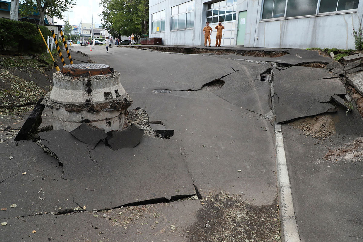 Residents look at the damage caused by an earthquake to a road in Sapporo, Hokkaido prefecture on 6 September 2018. Photo: AFP