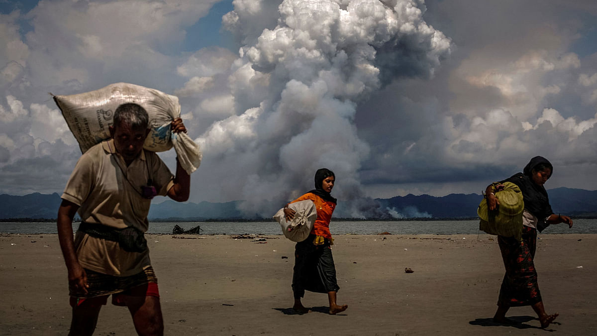 Smoke is seen on the Myanmar border as Rohingya refugees walk on the shore after crossing the Bangladesh-Myanmar border by boat through the Bay of Bengal, in Shah Porir Dwip, Bangladesh on 11 September 2017. Reuters File Photo