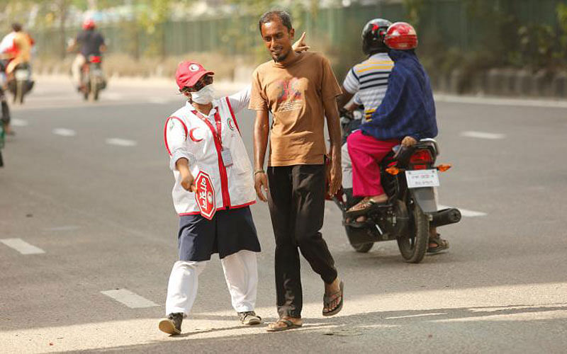 A volunteer from the Red Crescent Society directs a pedestrian to use the overbridge at Banglamotor, Dhaka on 8 September. Volunteers like her, for a month, have been helping control the traffic and raise public awareness about the rules. Photo: Sumon Yousuf