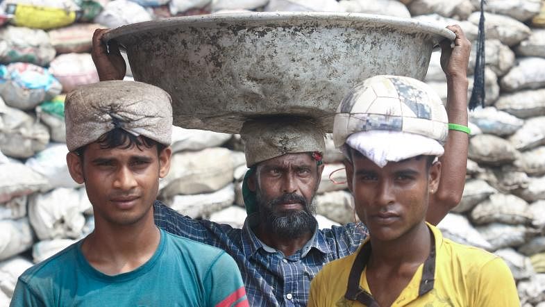 Three labourers are seen at a sanitary landfill dump in Matuail, Dhaka on 12 September. They collect paper, bones, glass, iron, plastics, and coconut husks from the waste and sell them to the local traders. Photo: Abdus Salam