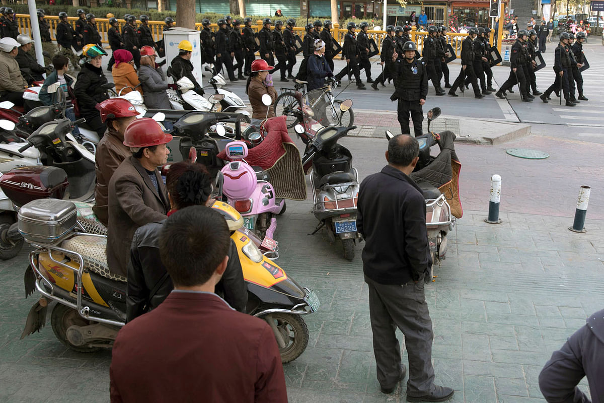 In this 5 November 2017 file photo, residents watch a convoy of security personnel in a show of force through central Kashgar in western China`s Xinjiang region. Photo: AP