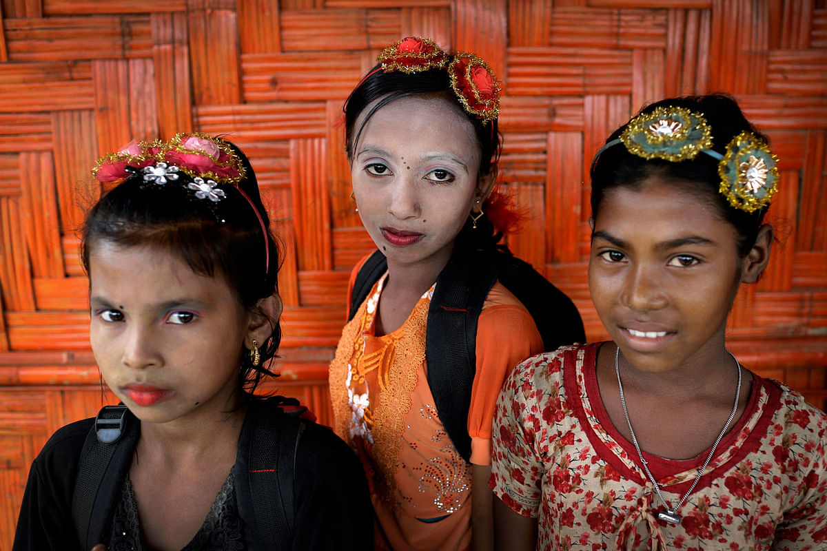 In this 27 June 2018 photo, from left, Ranjeda, 9, Rumana, 10, and Zesmin, 10 pose for a portrait in front of their classroom in Chakmarkul refugee camp, Bangladesh. Amid the misery and mud of Bangladesh`s refugee camps, Rohingya girls have found small moments of joy by adorning themselves with flowery headbands and elaborately-drawn makeup. Photo: AP