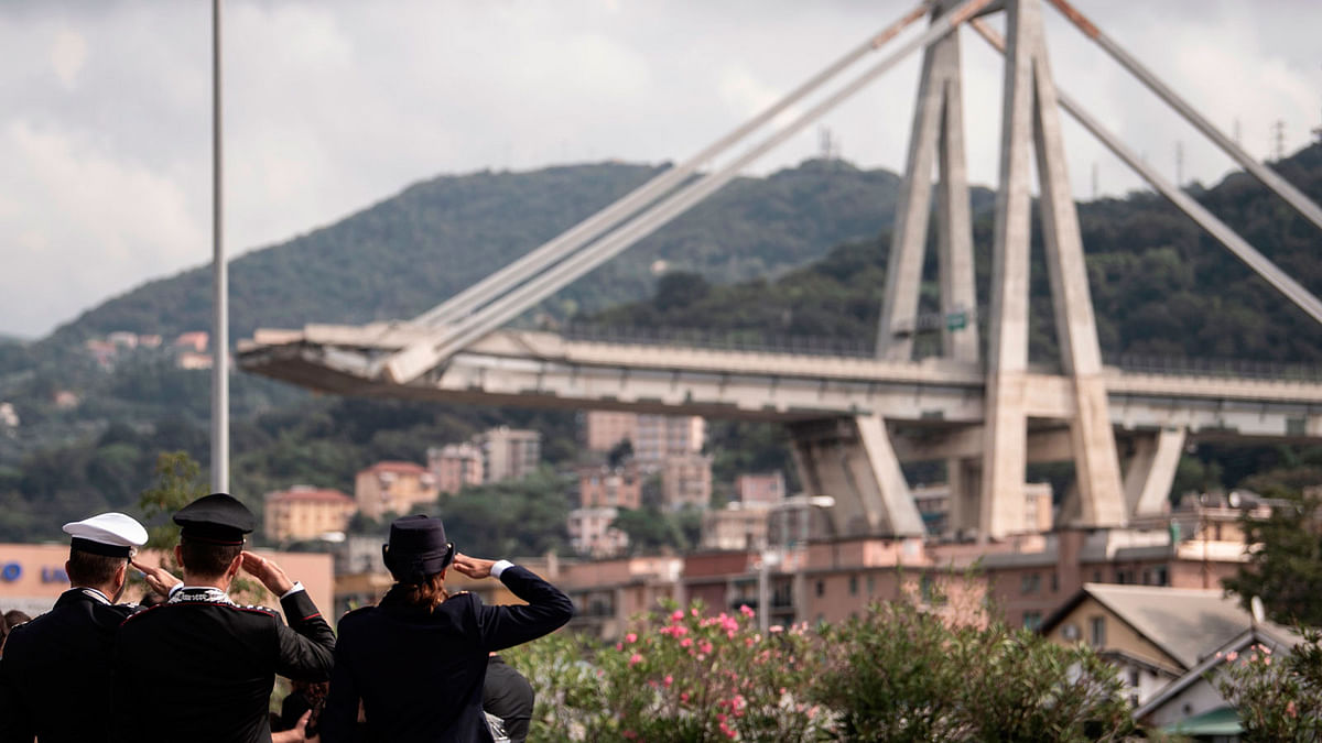Member of the Italian Police pay tribute to the victims during a minute of silence and a commemoration ceremony near the bridge`s wreckage, one month after the Morandi Bridge collapse that killed 43 people, on September 14, 2018 in Genoa. A month after Genoa`s Morandi Bridge collapse killed 43 people, the port city is tending to its wounds and those left homeless by the disaster are turning a brave face to the future. AFP
