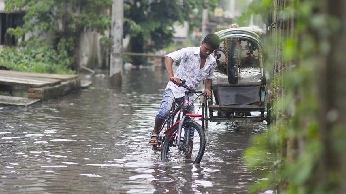 A biker struggles with his bicycle as he makes way through the flooded area of Matuail along DND dam in Dhaka on 14 September. The area was flooded with dirty water after it rained for two days at a stretch. Photo: Dipu Malakar