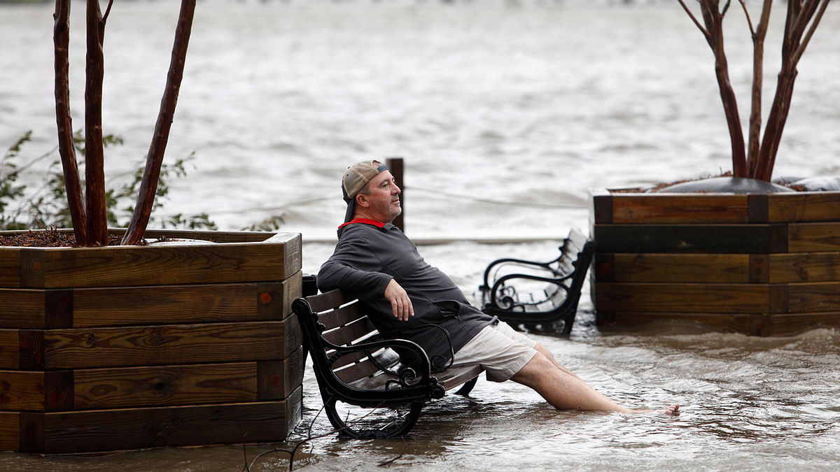 A man sits on a park bench in a flooded park as the Cape Fear River rises above its usual height in Wilmington, North Carolina, US, on 14 September 2018. Photo: Reuters
