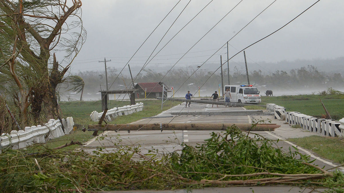Staff of an ambulance carrying a sick child try to clear a road of debris and toppled electric posts caused by strong winds from super Typhoon Mangkhut along a road in Baggao town in Cagayan province, north of Manila on 15 September 2018, as they try to bring the sick child to a nearby hospital of Tuguegarao city. Photo: AFP