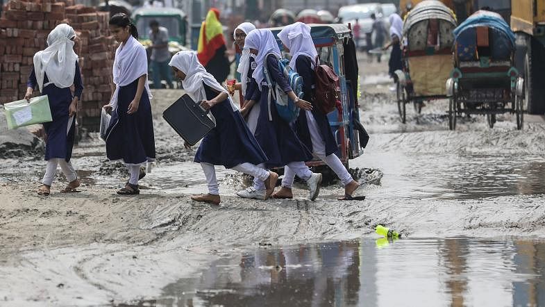 A group of students cross a road full of potholes and puddles at Canal Par, Pashchim Tengra, Demra, Dhaka on 15 September. Photo: Dipu Malakar
