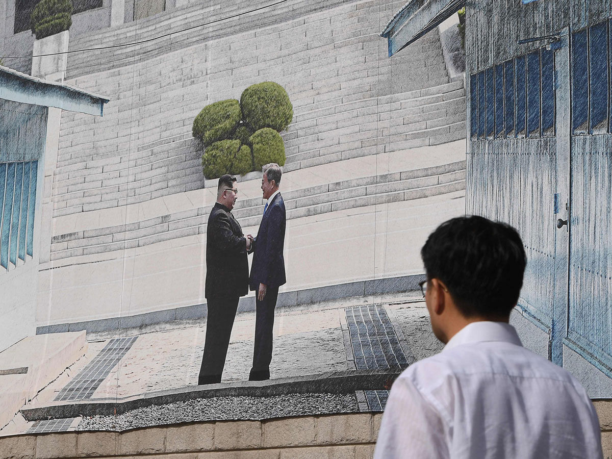 A man walks past a giant banner showing a picture of the summit handshake between South Korean President Moon Jae-in and North Korean leader Kim Jong Un, at Seoul City Hall on 13 September 2018. Photo: AFP