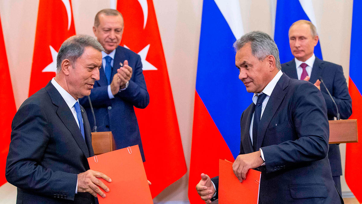 Russian defence minister Sergei Shoigu (R) exchanges documents with Turkish defence minister Hulusi Akar (frontL) as Russian president Vladimir Putin (backR) and Turkish president Recep Tayyip Erdogan applaud during a joint press conference following the talks, in the Bocharov Ruchei residence in the Black Sea resort of Sochi in Sochi on 17 September. Photo: AFP