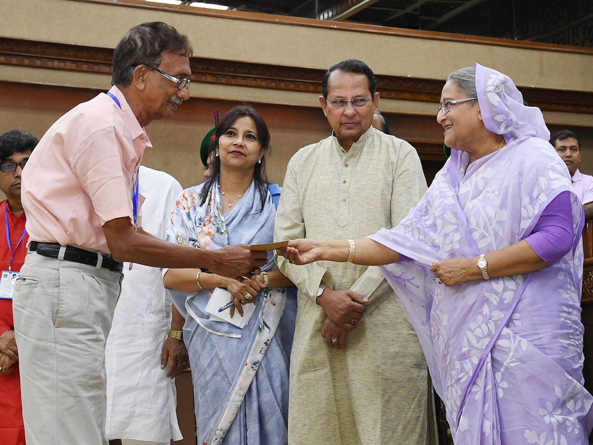 Prime minister Sheikh Hasina hands over a cheque to a journalist at the PMO in Dhaka on Wednesday. Photo: PID