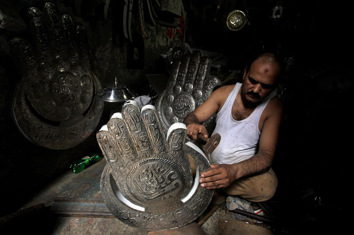A man shapes a religious symbol for sale, in preparation for the Ashura procession, at a workshop in Lahore, Pakistan on 11 September 2018. Photo: Reuters
