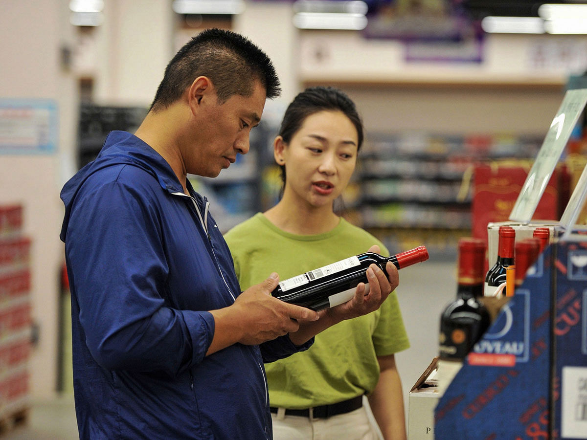 A customer selects imported alcohol at a store in Qingdao in China`s eastern Shandong province on 19 September, 2018. Photo: AFP