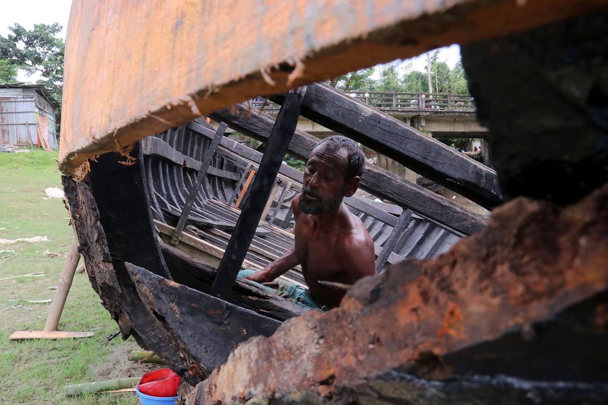 A man repairs a boat at Tukerhat, Sylhet on 20 September. Photo: Anis Mahmud