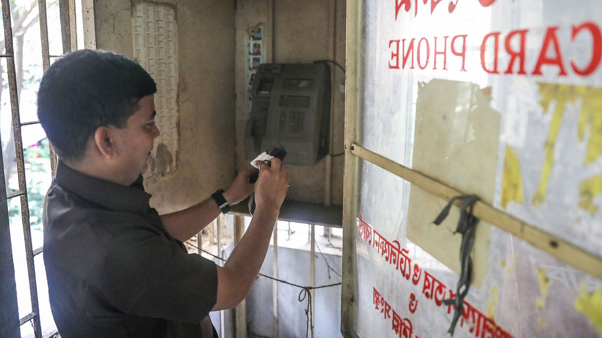 A man cleans the telephone booth at the head post office of Dhaka division in Banglabazar on 17 September. The booth was last used 12 years ago. Photo: Dipu Malakar