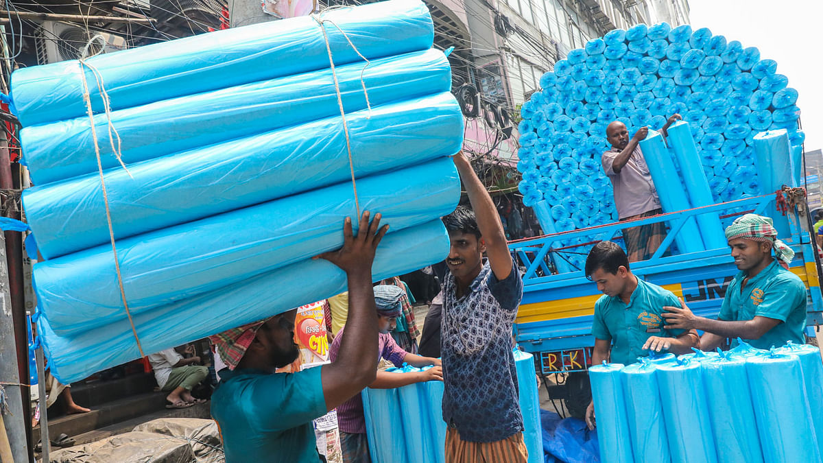 Workers unloading rolls of paper lining. The rolls are brought from Narsingdi and sold at the wholesale cloth market in Islampur, Sadarghat in Dhaka. 17 September. Photo: Dipu Malakar