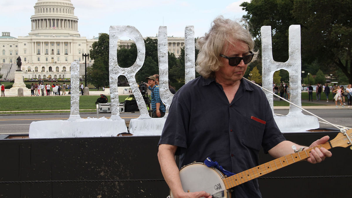 A man plays the banjo in front of an ice sculpture spelling out the word `truth` by artist duo LigoranoReese after its second `t` melted, with the US Capitol in the background, in Washington on 22 September 2018. Photo: Reuters