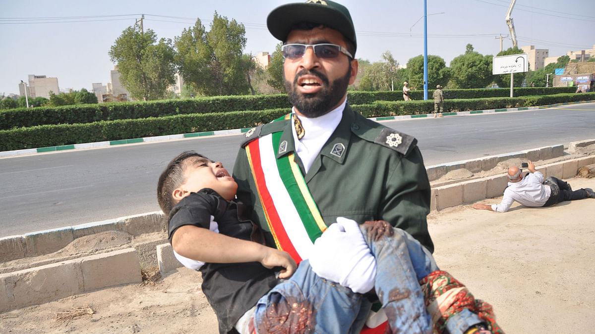 This picture taken on 22 September in the southwestern Iranian city of Ahvaz shows a member of Iran`s Revolutionary Guards Corps (IRGC) carrying an injured child at the scene of an attack on a military parade that was marking the anniversary of the outbreak of its devastating 1980-1988 war with Saddam Hussein`s Iraq. Photo: AFP