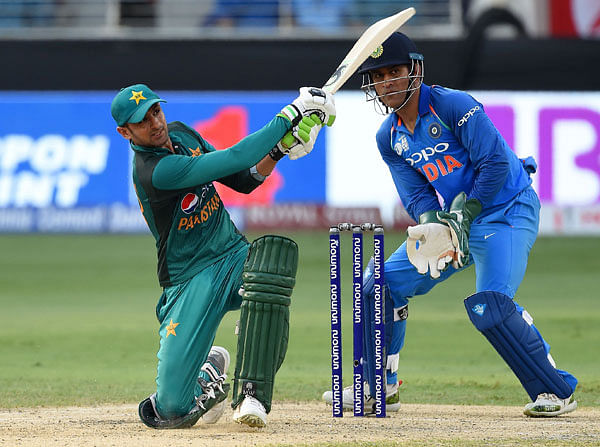 Pakistan batsman Shoaib Malik plays a shot as Indian wicketkeeper Mahendra Singh Dhoni (R) looks on during the one day international (ODI) Asia Cup cricket match between Pakistan and India at the Dubai International Cricket Stadium in Dubai on 23 September 2018. Photo: AFP
