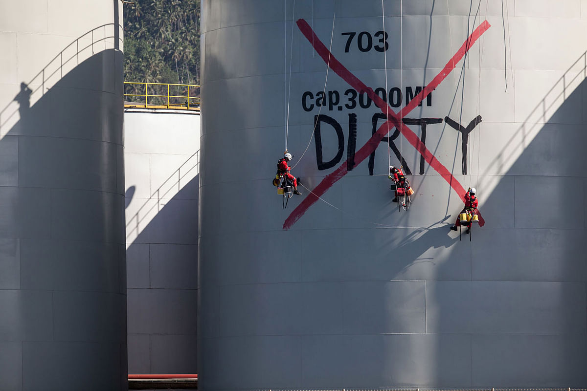 This handout picture taken on 25 September 2018 and released by Greenpeace Southeasia shows Greenpeace activists painting `DIRTY` onto a silo at Wilmar International refinery in Bitung, North Sulawesi. Photo: AFP