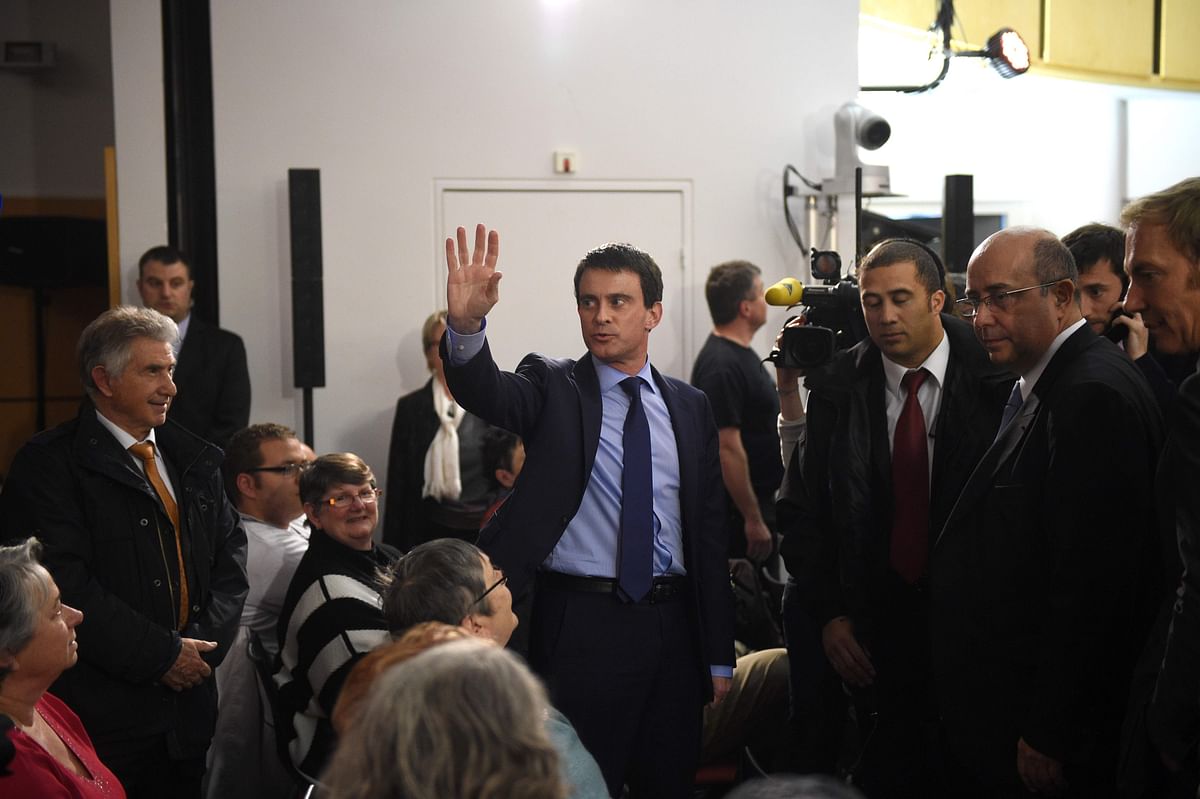 In this file photo taken on April 4, 2014 in Evry, French Prime Minister Manuel Valls (C) waves as he arrives to attend a city municipal council. The city of Evry says `Adios` and `good luck` to Manuel Valls, former Evry mayor and deputy and former French prime minister, as he is to announce on September 25 if he will run in Barcelona’s mayoral election. AFP