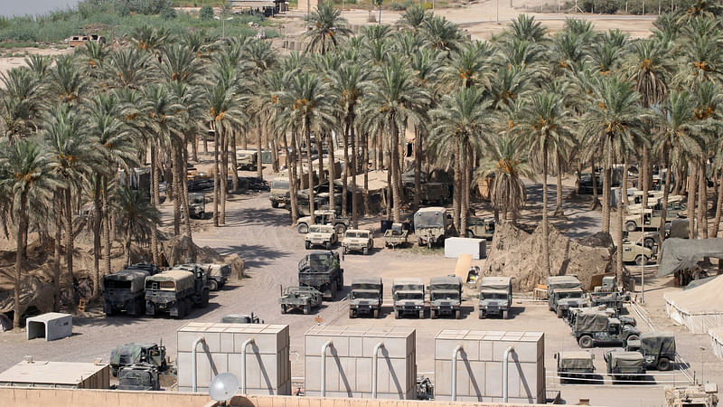 US Military vehicles parked among a grove of date palm trees at Camp Babylon, Iraq, during Operation Iraqi Freedom. Photo: Collected