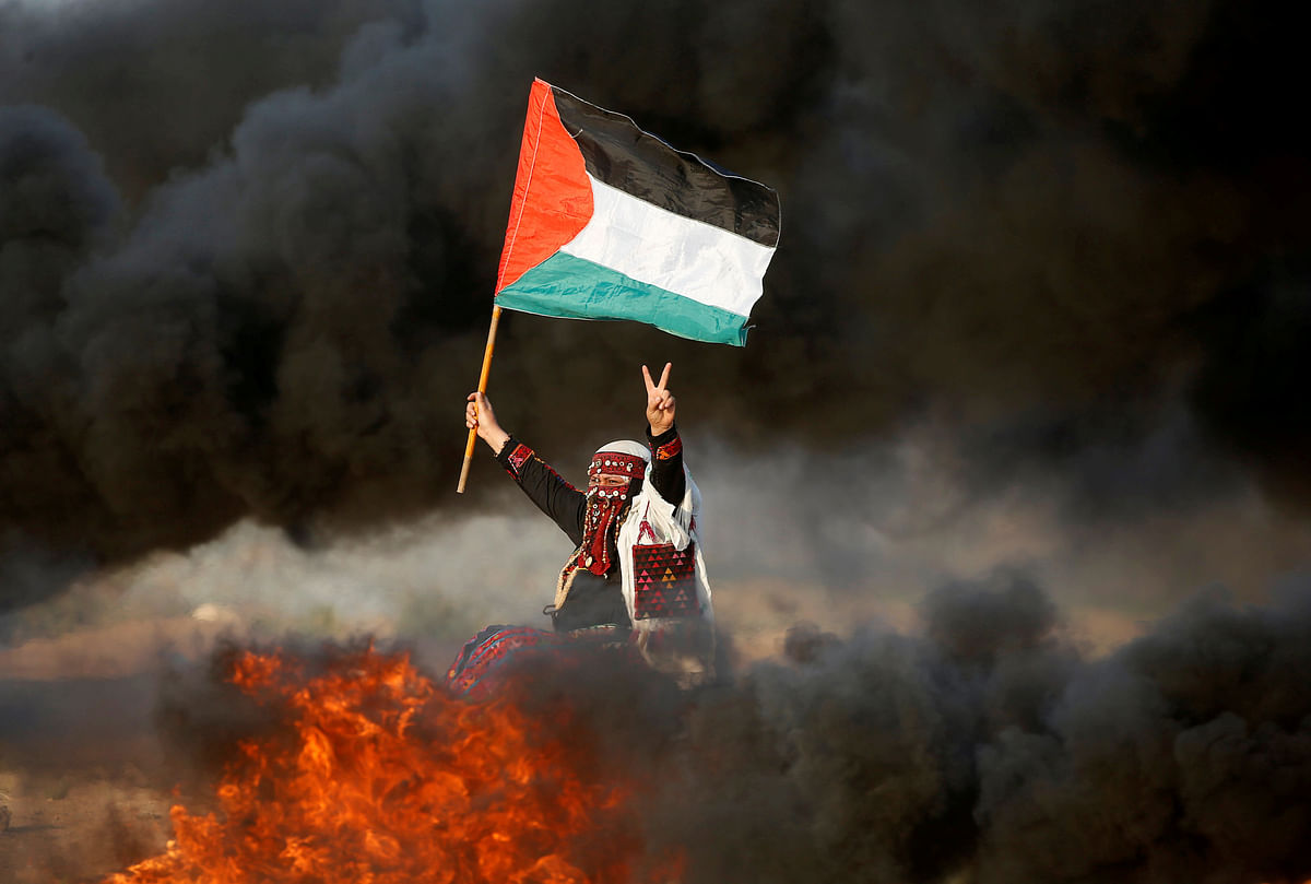 A woman waves a Palestinian flag during a protest calling for lifting the Israeli blockade on Gaza and demanding the right to return to their homeland, at the Israel-Gaza border fence east of Gaza City on 28 September. Photo: Reuters