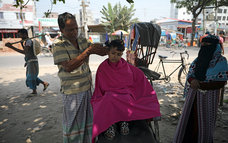 A boy takes a haircut at a roadside salon in Dhaka, Bangladesh on 2 October 2018. Photo: Reuters
