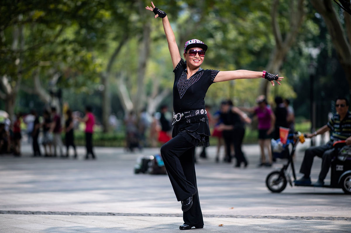 This picture taken on 2 September 2018 shows a woman from a square dancing team striking a pose for a photograph in a public park in Shanghai. Photo: AFP