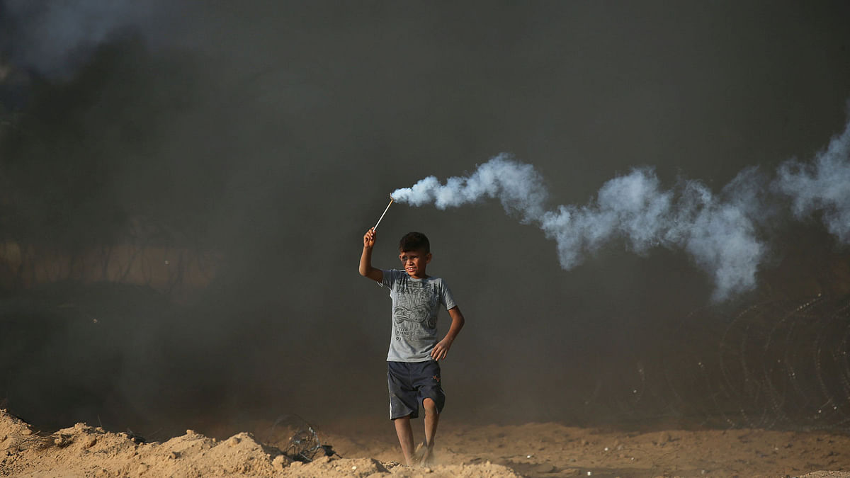 A Palestinian boy holds a tear gas canister fired by Israeli troops during a protest calling for lifting the Israeli blockade on Gaza and demanding the right to return to their homeland, at the Israel-Gaza border fence in the southern Gaza Strip on 5 October 2018. Photo: Reuters