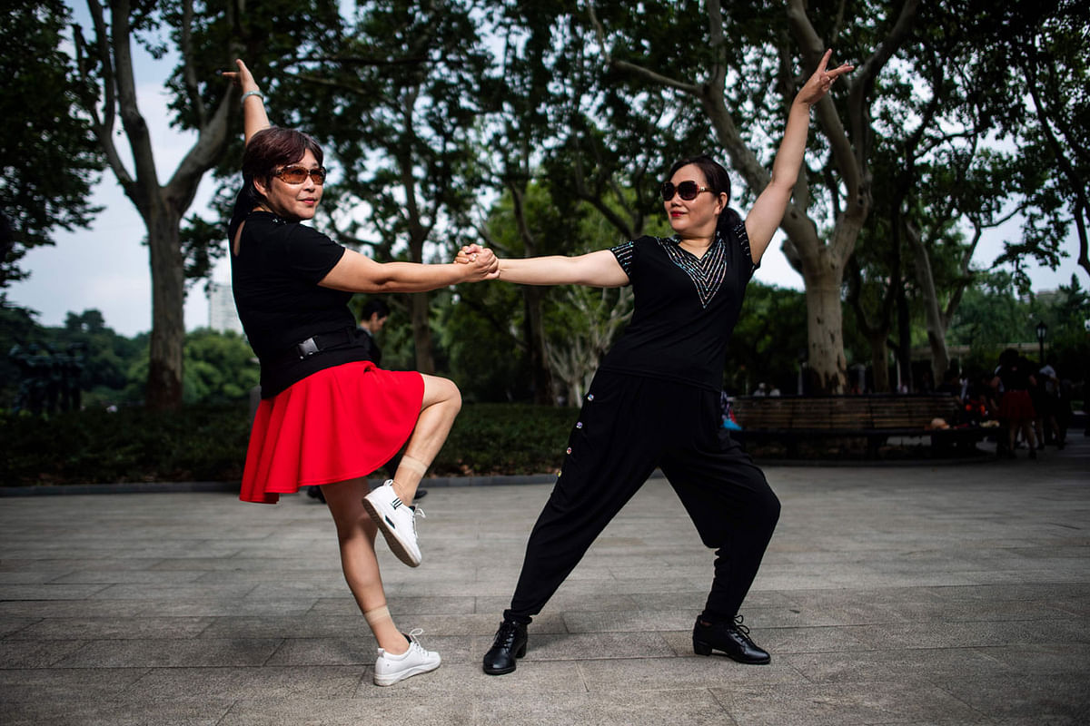 This picture taken on 2 September 2018 shows a dancing couple striking a pose for a photograph in a public park in Shanghai. Photo: AFP