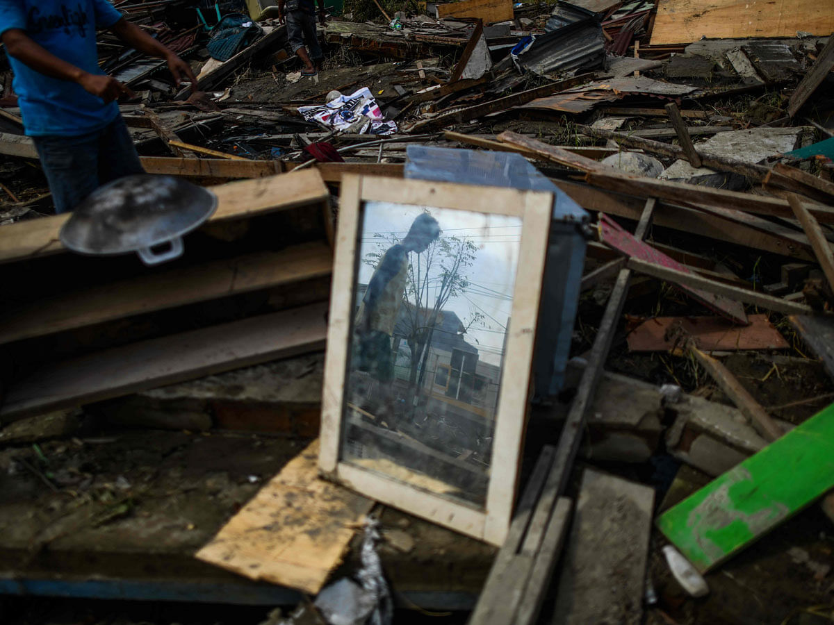 An earthquake-affected resident is reflected on a mirror as he searches for salvageable items at a collapsed market in Palu, Indonesia`s Central Sulawesi on 4 October 2018, after an earthquake and tsunami hit the area on 28 September. Photo: AFP