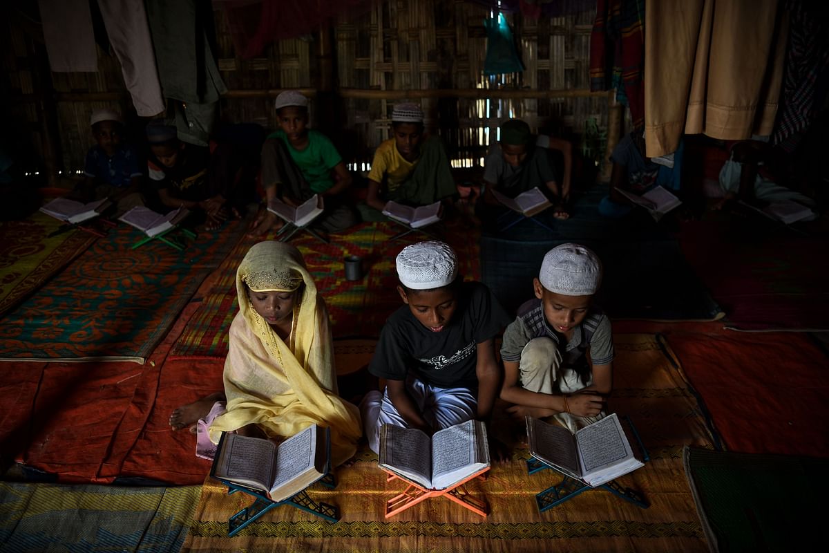 In this photograph taken on 12 August, Saleema Khanam (L), 8, studies inside a makeshift madrassa (Islamic seminary) with other boys in Kutupalong camp, in Ukhia near Cox`s Bazar. Photo: AFP