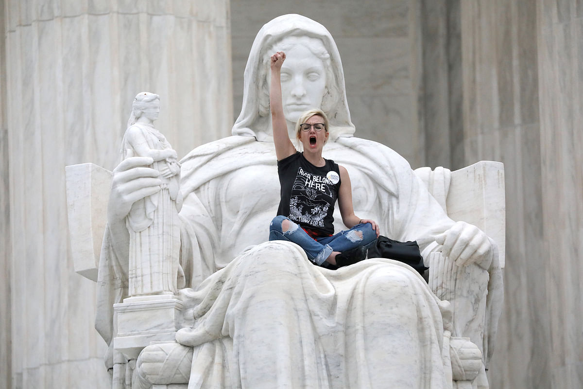 A protester sits on the lap of `Lady Justice` on the steps of the US Supreme Court building as demonstrators storm the steps and doors of the Supreme Court while Judge Brett Kavanaugh is being sworn in as an Associate Justice of the court inside on Capitol Hill in Washington, US, 6 October 2018. Photo: Reuters