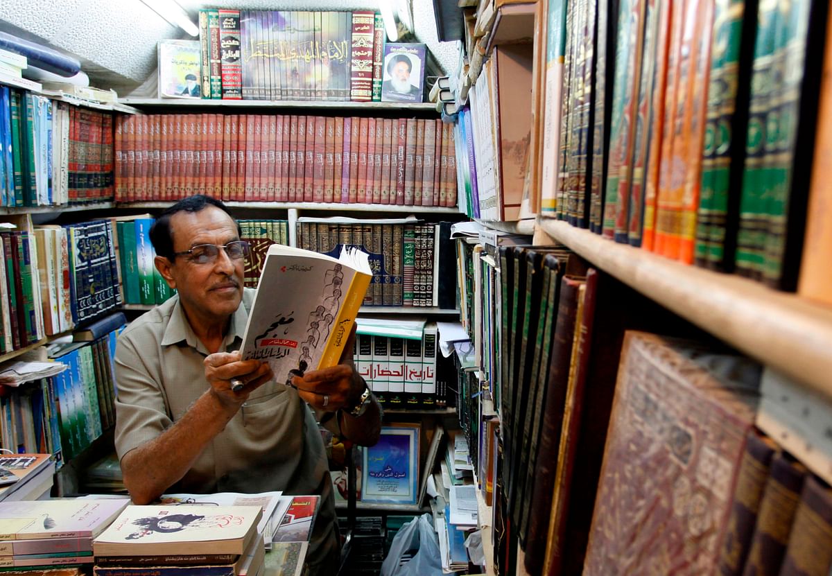 An Iraqi man reads a book at a shop in the Howeish book market in the holy city of Najaf, 150 kilometres (95 miles) south of Baghdad, on 16 August 2018. Photo: AFP