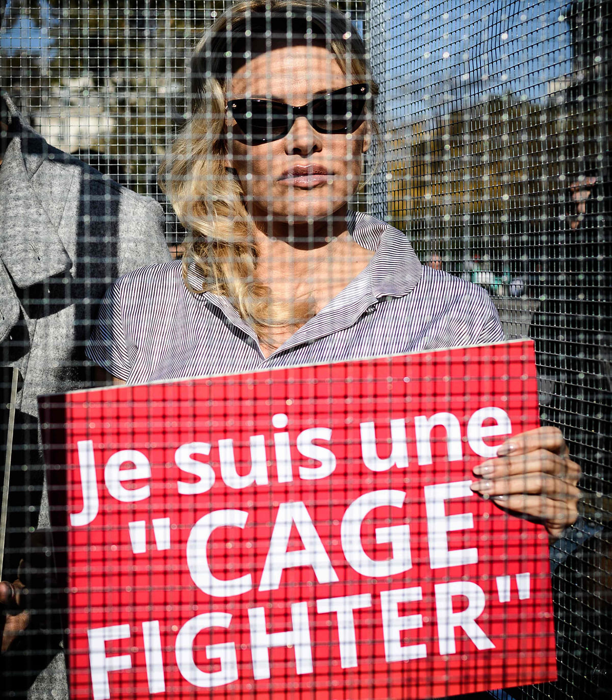 US-Canadian actress Pamela Anderson (R) and her dancing partner Maxime Dereymez stand in a cage displaying placards against the caging of animals during an event organized by the NGO Compassion in World Farming (CIWF) in Paris on 10 October 2018. Photo: AFP