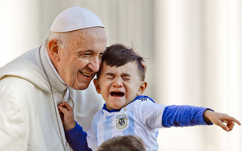 Pope Francis caresses a child as he arrives on his popemobile in St Peter`s Square for his weekly general audience at the Vatican, 10 October. Photo: AP