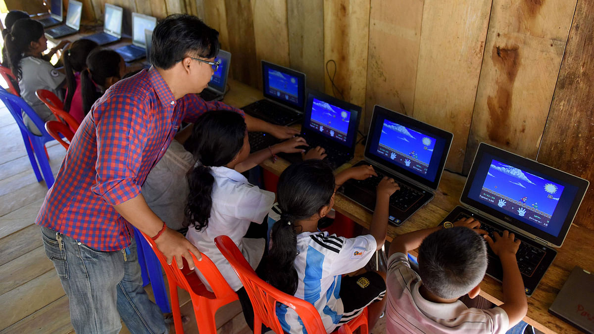 This photo taken on 1 October 2018 shows a teacher tending to students learning the use of computers at the Coconut School at Kirirom national park in Kampong Speu province. Photo: AFP