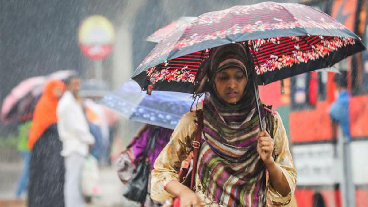 A woman walks in capital`s Mohakhali with an umbrella during rain caused by cyclone Titli on the Bay of Bengal. Photo: Dipu Malakar