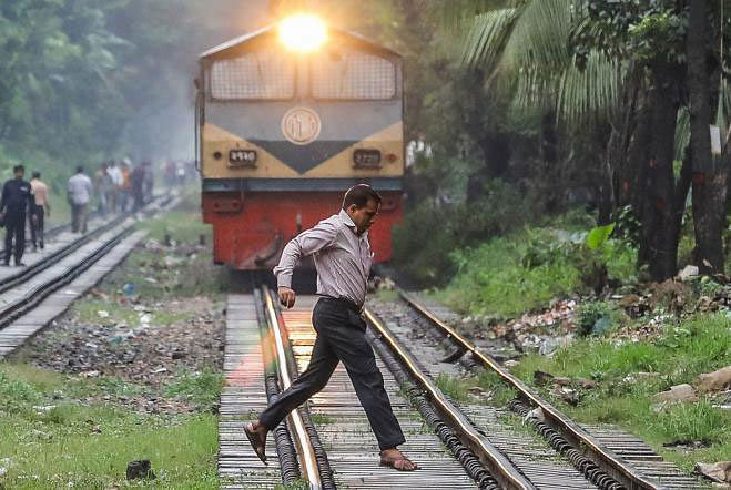 A man crosses the railway line taking risk while the train approaches in Mohakhali Rail Crossing. Photo: Dipu Malakar