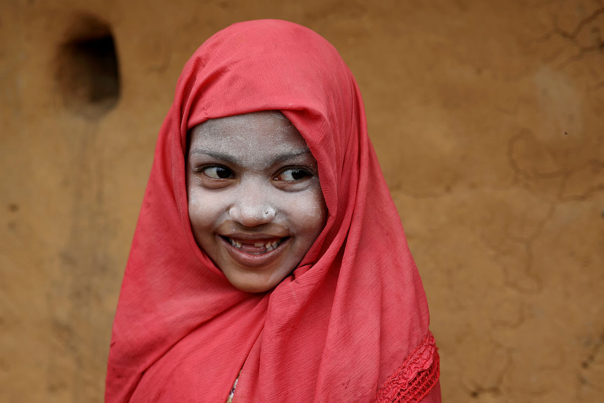 A Rohingya refugee girl smiles as she applies Thanaka paste in the Kutupalong camp in Cox`s Bazar, Bangladesh, 13 October 2018. Photo: Reuters